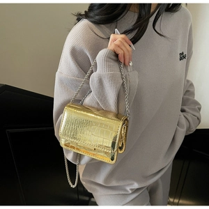 Close-up of golden crocodile embossed leather crossbody bag with elegant silver chain