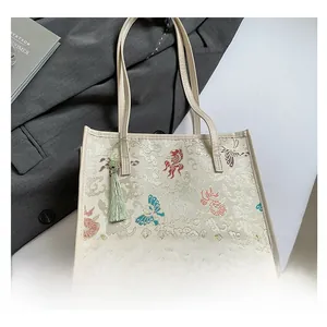 Close-up of jacquard tote bag with traditional fish pattern and green tassel detail