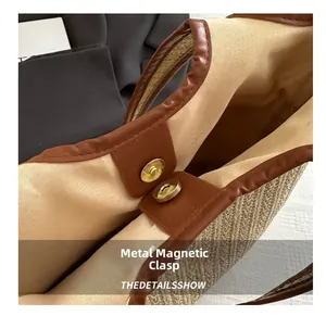 Detail of metal magnetic buckle on a woven straw tote bag with brown leather trim
