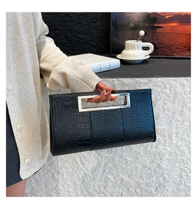 Detail of black croc-embossed clutch with modern silver hollow rectangular metal handle