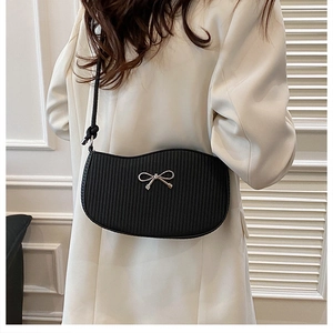 Detail of black wavy shoulder bag featuring a gold bow accent and striped texture