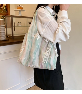 Détail de rubans en dentelle et broderie florale sur un sac cabas effet marbré