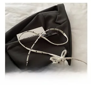 Close-up of quilted white crossbody bag featuring black patterns and drawstring bow strap