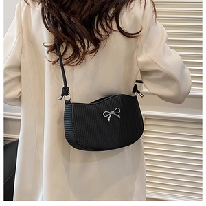 Detail view of black crescent shoulder bag with silver bow buckle on model's back