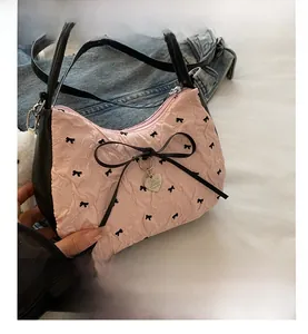 Détail du sac froncé rose avec nœud noir et pendentif en forme de cœur argenté
