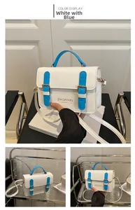 Detail of white and blue crossbody bag showing golden metal buckles and flap texture
