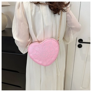 Close-up of pink heart-shaped crossbody bag with spider web stitching and gold chain strap