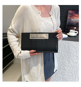 Detail of black crocodile texture clutch with polished rectangular metal top handle