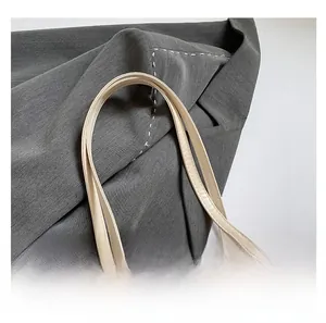 Detail shot of cream leather dual handles with refined stitching on a Chinese style tote