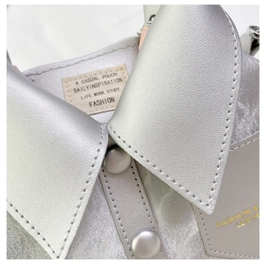 Detailed macro view of silver metallic collar design and texture on small square bag