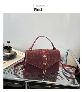 Detail of red crossbody handbag with embossed flap on a modern display shelf