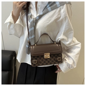 Detail of vintage crossbody bag with Monogram print and gold lock worn by model
