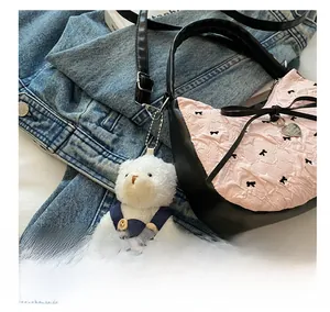 Gros plan d'un charme ours en peluche sur un sac plissé rose et noir avec nœuds