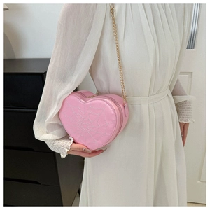 Detail of pink heart-shaped bag with spider web embroidery and golden chain strap