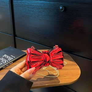 Elegante pochette a fiocco rosso metallizzato con catena dorata tenuta in mano