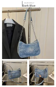 Detail of dark blue denim underarm bag with silver chain and smooth zipper closure