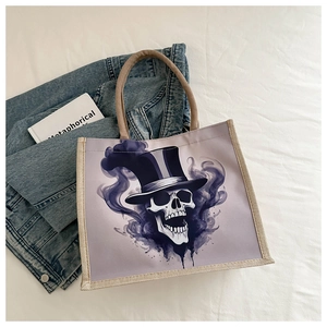 Détail macro du sac cabas en toile avec imprimé crâne violet et poignées en corde sur tissu blanc