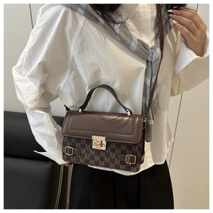 Detail of a dark brown crossbody bag with vintage M-pattern embroidery and metallic buckle