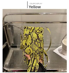 Detail of a yellow snakeskin pattern mini crossbody bag with long fringes and metal buckle