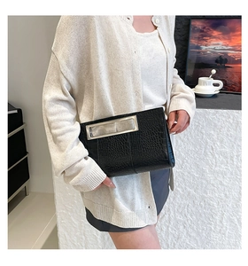Detail of black crocodile texture handbag featuring a silver rectangular metal handle