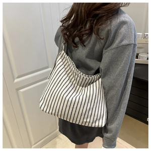 Vue arrière d'un grand sac cabas en toile à rayures bleues et blanches porté par un mannequin