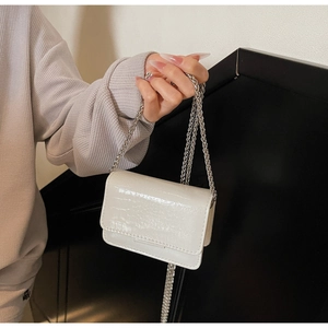 Detail of white crocodile texture patent leather mini bag with silver chain strap