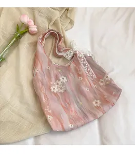 Détail de broderie florale rose et nœud en dentelle sur un sac fourre-tout chic
