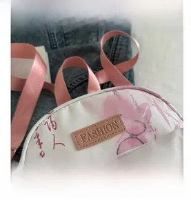 Detail eines weißen Mini-Rucksacks mit rosa Schmetterlingsdruck und modischem Lederetikett
