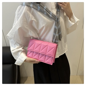 Pink quilted shoulder bag with silver chain strap shown worn across a person's body