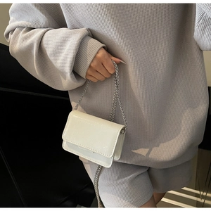 Detail of cream patent faux-crocodile mini bag with silver chain strap and metal finish
