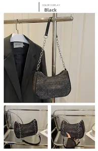 Detail view of black glitter denim baguette bag with silver chain strap and crescent shape
