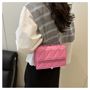 Rear view of a model wearing a pink quilted crossbody bag with a silver chain strap