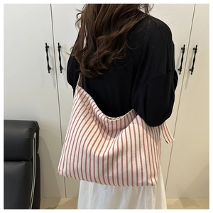 Gros plan détaillé montrant la texture en toile rayée rouge et blanc de ce grand sac cabas