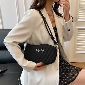 Minimalist black woven shoulder bag with silver bow accent and knot strap on model
