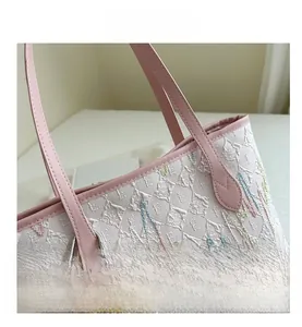 Close-up of white tote bag featuring colorful wave embroidery and a cute bear charm