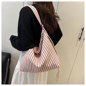 Model wearing a large red and white striped canvas tote bag in a casual interior setting