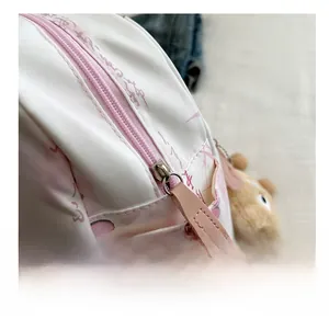 Nahaufnahme des rosa Reißverschlusses und Bärenanhängers am geblümten Rucksack