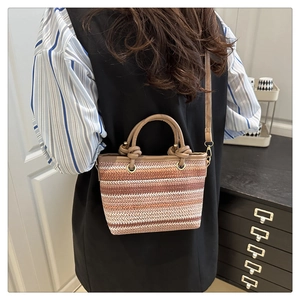 Detail einer handgewebten Strohtasche mit Streifenmuster und Umhängeriemen am Modell