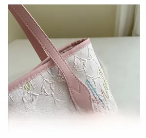 Detailed close-up of white diamond textured tote bag with pink leather trim and stitching