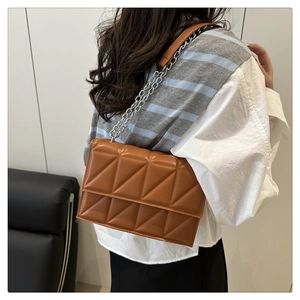 Brown quilted crossbody bag with silver chain strap worn by model in a stylish outfit
