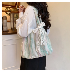 Détail du sac cabas en toile avec broderie florale et grand nœud décoratif en dentelle