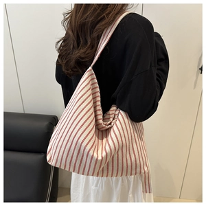 Detailed view of a large red and white striped canvas tote bag worn by a model