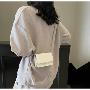 Mini white leather crossbody bag with chain strap shown on model for a minimalist look