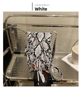 Detail of white snakeskin pattern crossbody bag featuring stylish fringe and adjustable strap
