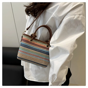 Detailed close-up of multi-colored striped woven beach bag with premium leather straps