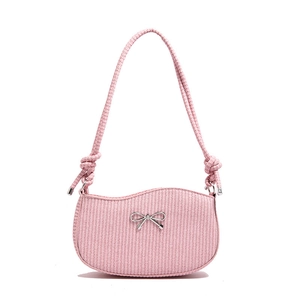 Pink woven baguette bag with silver bow accent and thick rope shoulder strap in flat lay