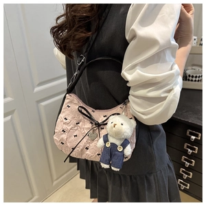 Détail du sac plissé rose avec broderie de nœud noir et pendentif cœur plus un ours en peluche