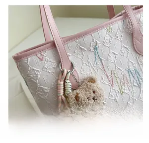 Detail of white embossed tote bag with pink leather trim and a cute plush bear charm