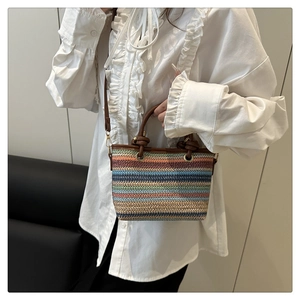 Detail der bunt gestreiften Strohbeuteltasche mit braunen Ledergriffen und Schultergurt