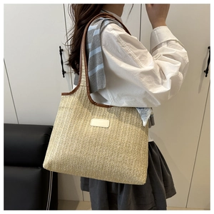 Detail of hand-woven straw tote with premium brown faux leather trim and long handles
